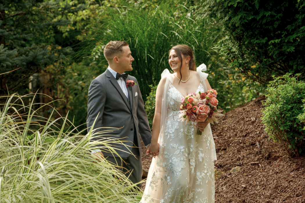 bride and groom hand in hand walking through gardens