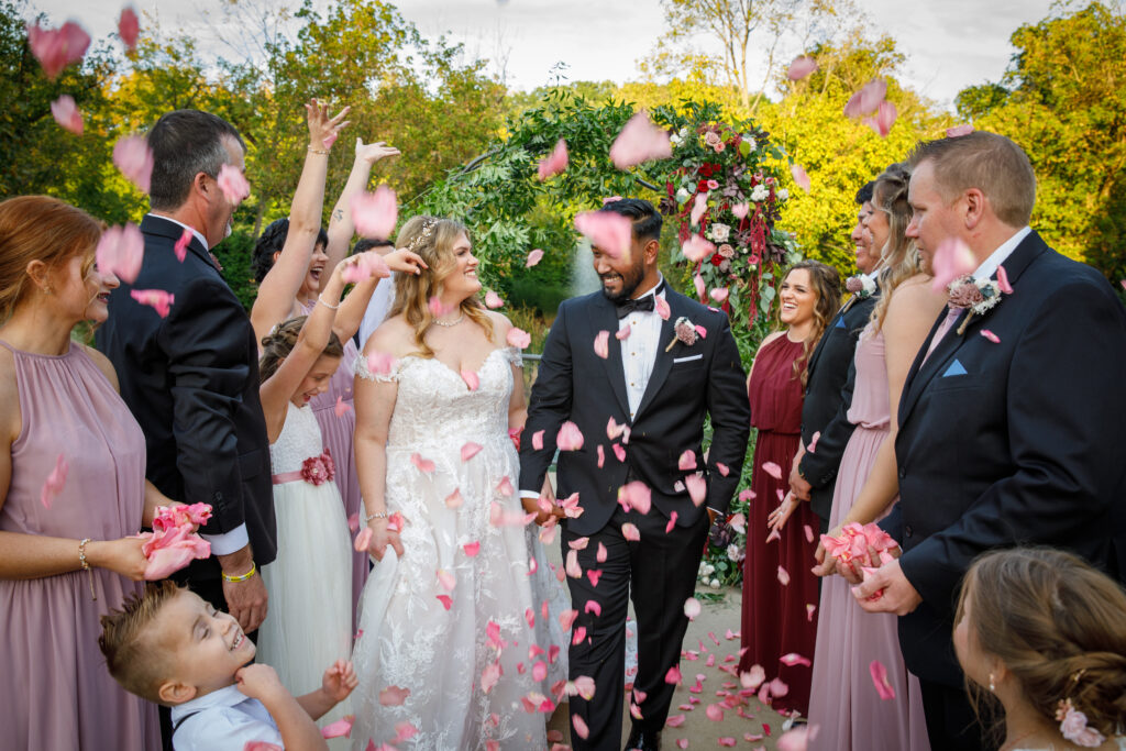 bride and groom walking down aisle with guests throwing flower petals