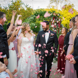 bride and groom walking down aisle with guests throwing flower petals