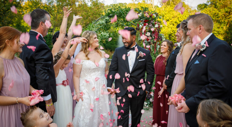 bride and groom walking down aisle with guests throwing flower petals